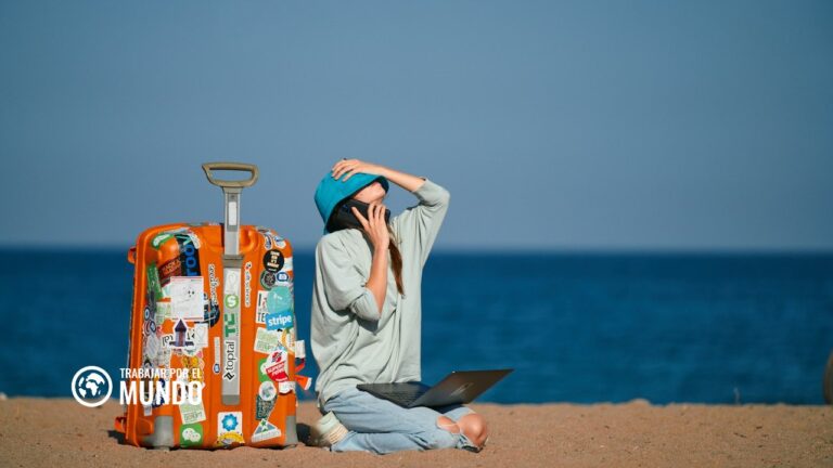 Viajera con maleta hablando por el móvil en la playa, eSIM para viajar